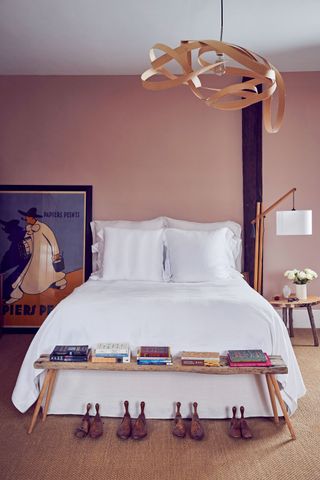 double bedroom with pink walls and white linen and wooden bench