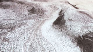 wispy snow stretches across a reddish-brown landscape