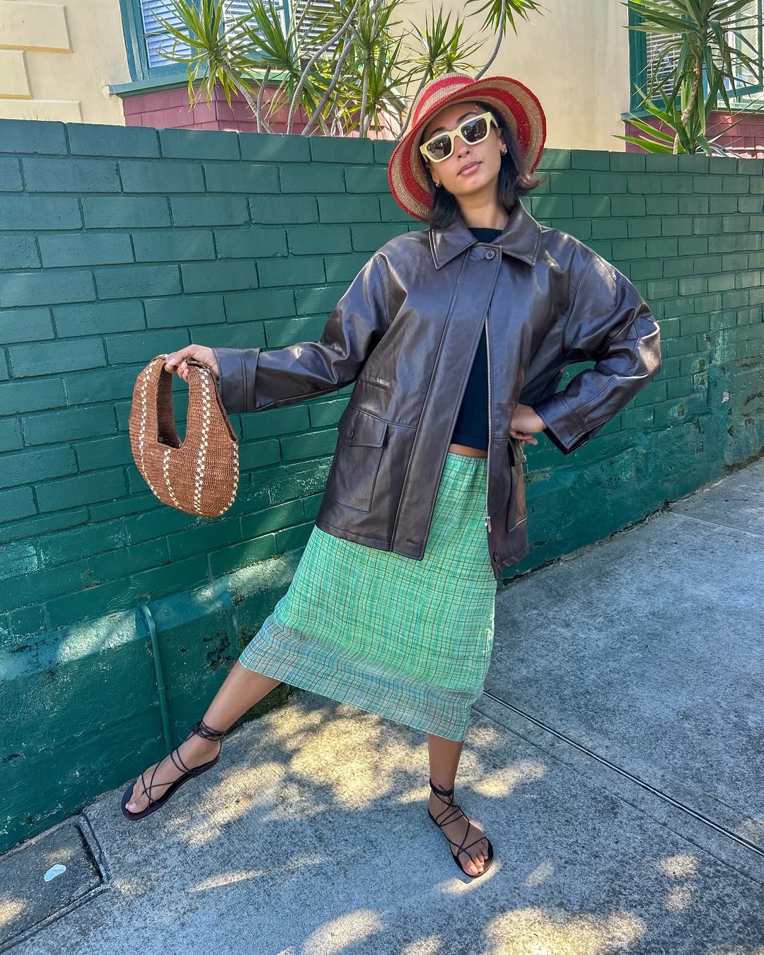 Barbara Santiago in a green skirt leather jacket black top holing a black band and black lace up leather shoes.