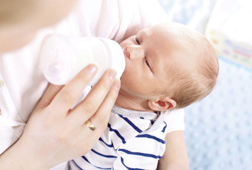 A woman feeds a baby.