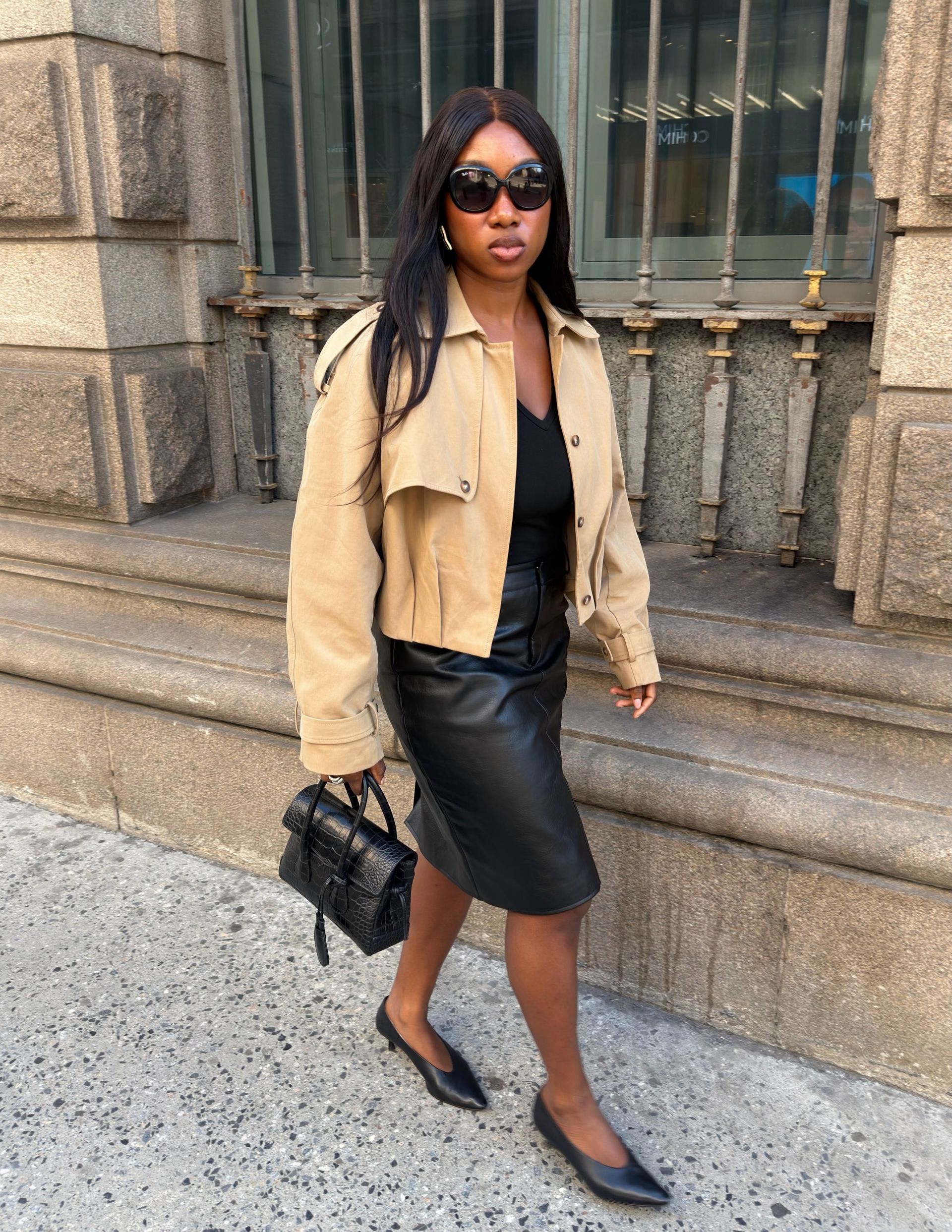 Woman in a beige jacket and black leather skirt