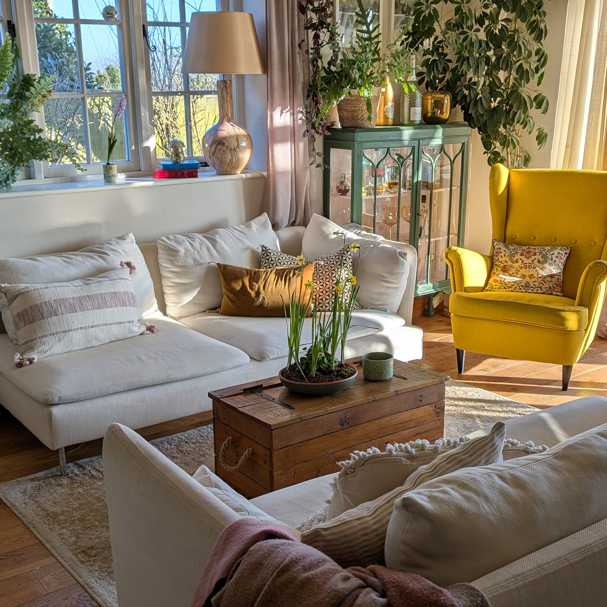 living room with bright yellow armchair, white sofa and chaise lounge and a wooden trunk used as a coffee table