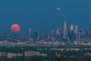 An airplane passes over New York City and the full Thunder Moon on Sunday (July 9) at 8:50 p.m. EDT (0050 GMT on July 10).
