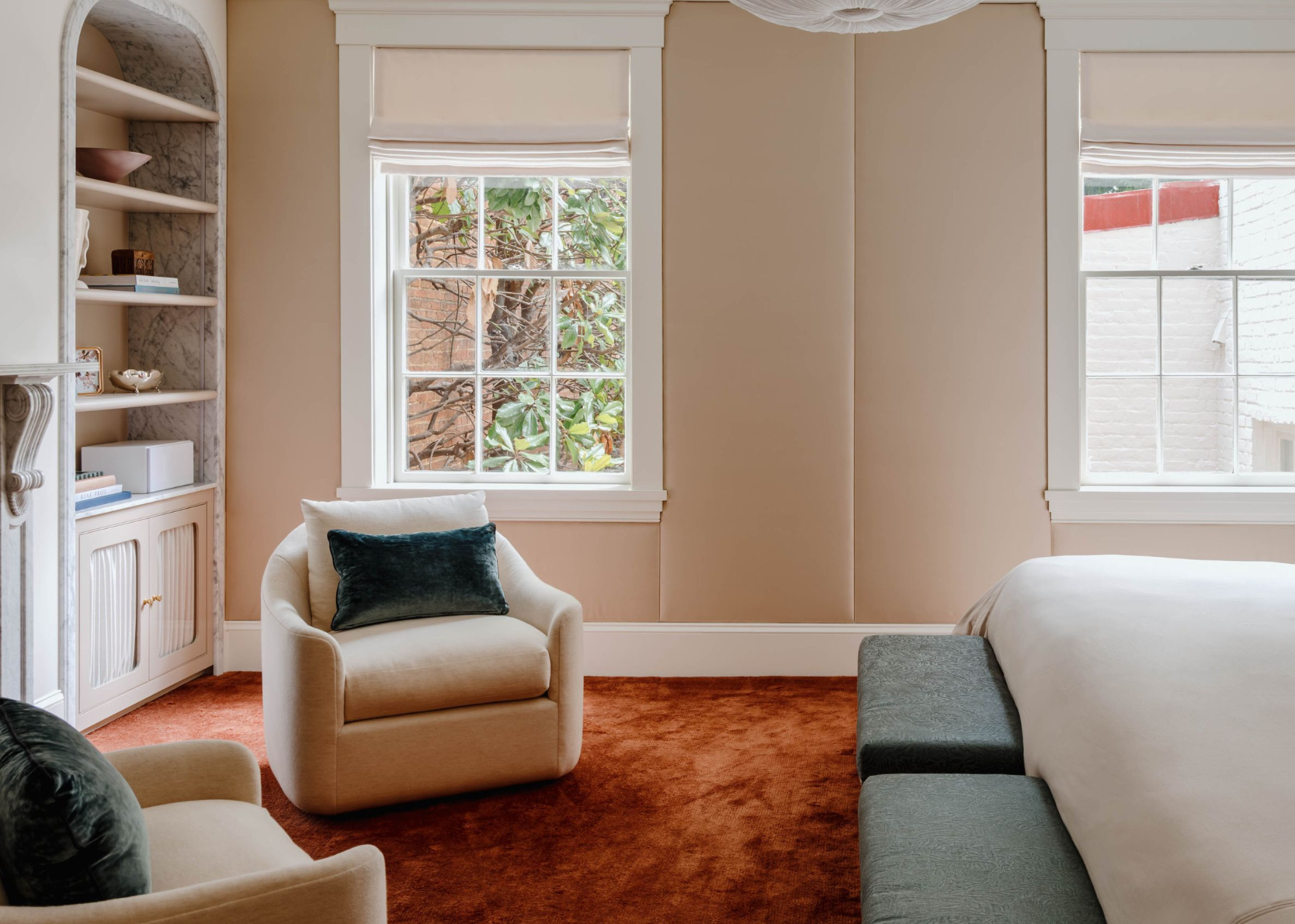 peach colored bedroom with orange carpet, beige bedding, and two windows