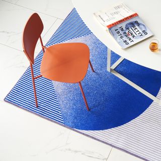 A blue rug by BCXSY for ZaoZuo pictured under a white table and red chair