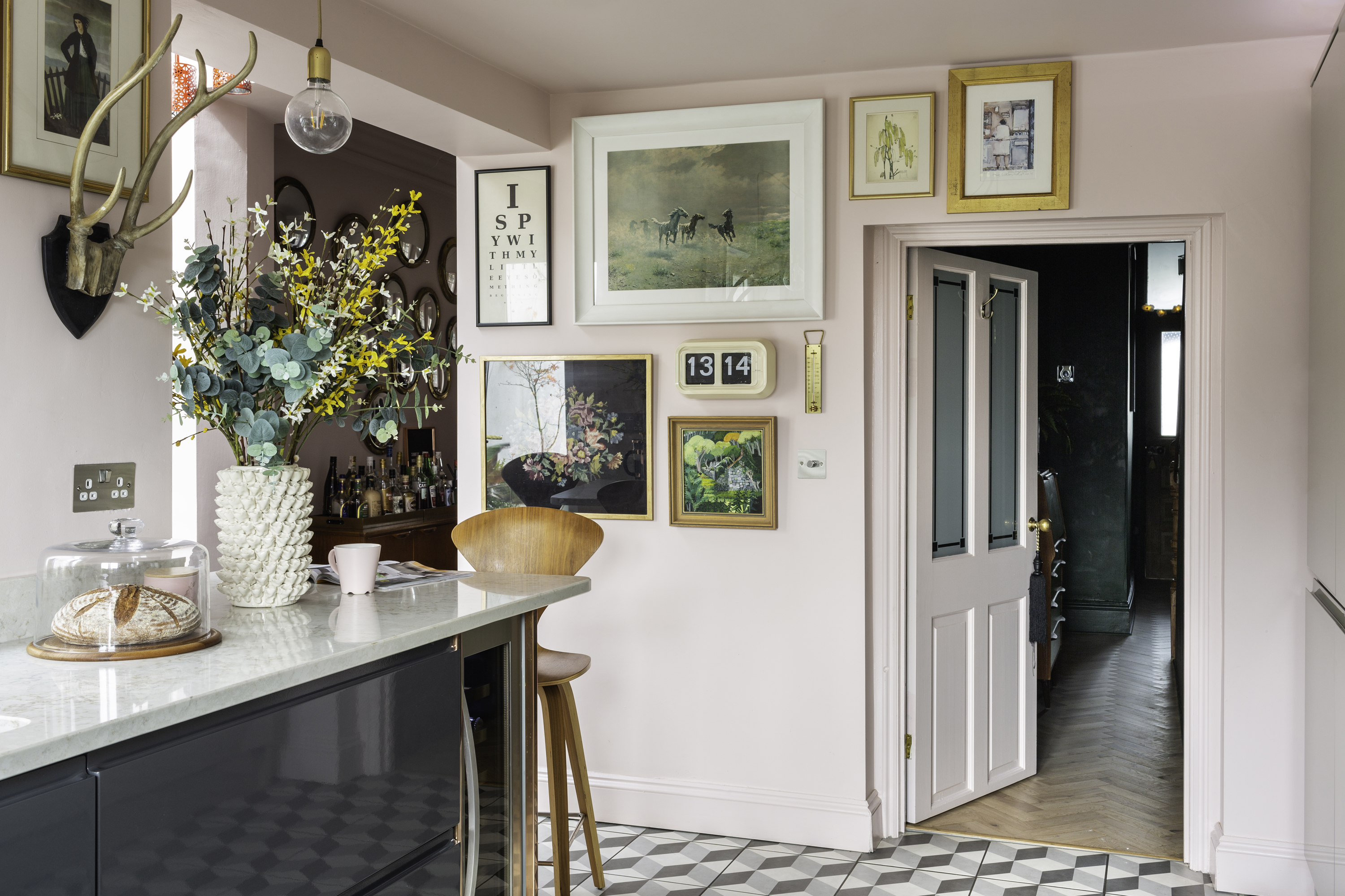 The kitchen floor has 3D-effect patterned tiles, which contrast with the pale pink of the walls