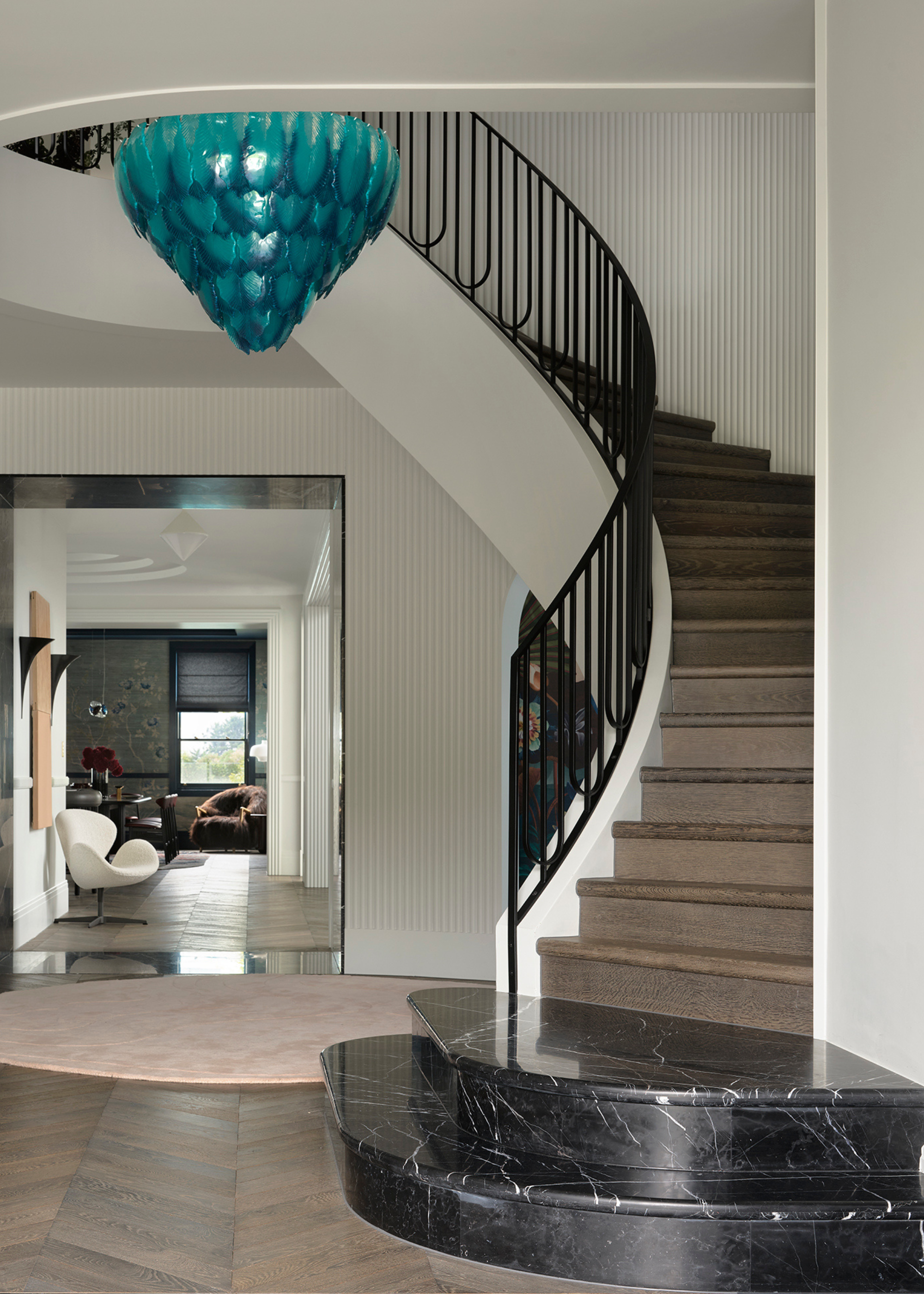 curving staircase with black metal balustrades, timber steps and a black marble landing