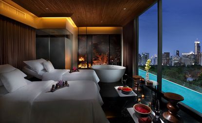 Bedroom in dark wood tones with a white bath and overlooking the city
