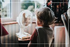 child standing in front of electric fan at home