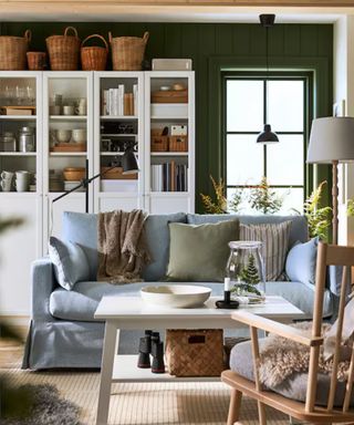 Pale blue loveseat with cushions, wooden furniture and bookshelf