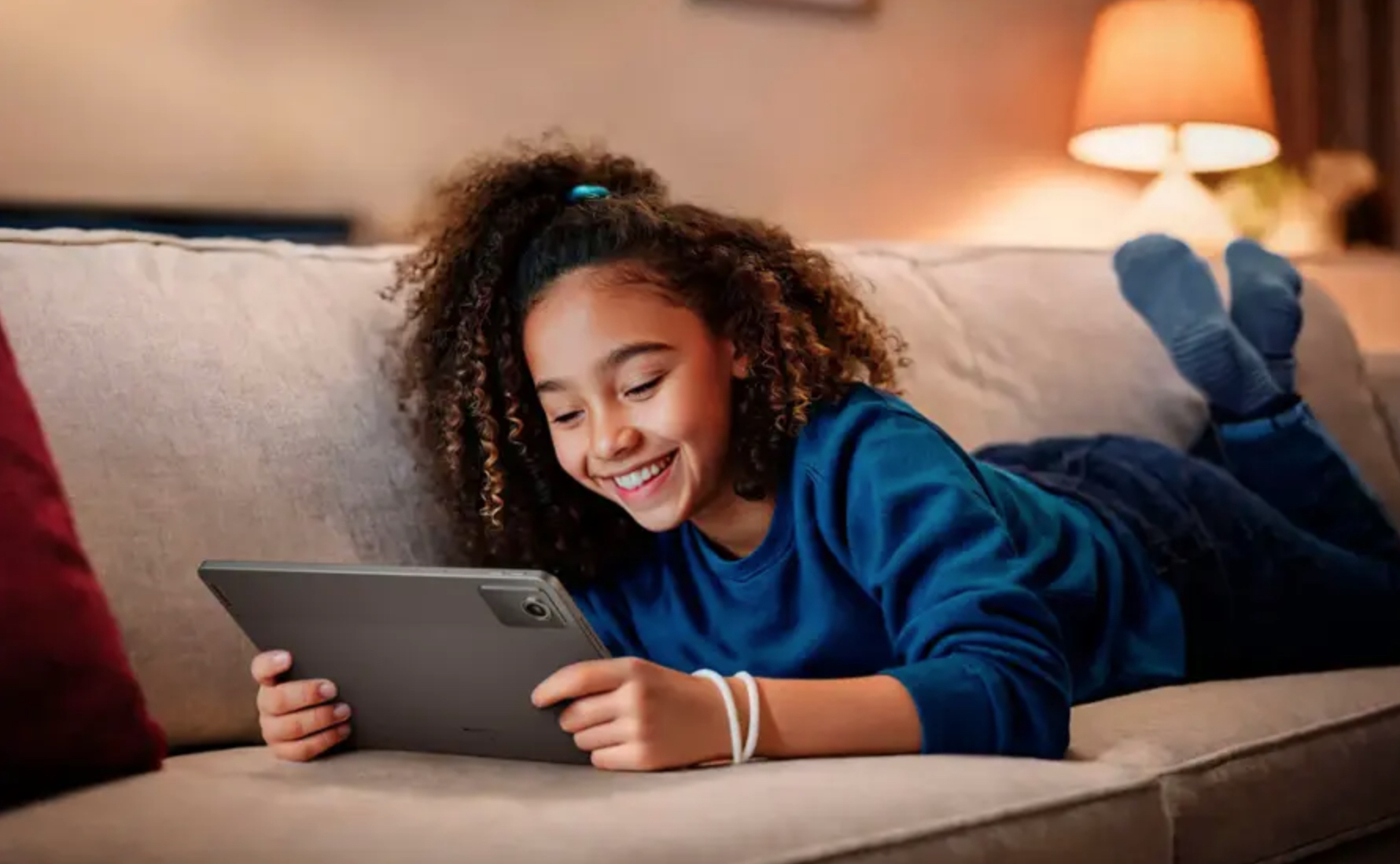 A person laying on the couch with a Lenovo tablet