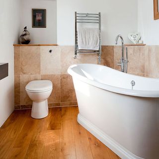 bathroom with wooden floor and bathtub with commode and towel rail