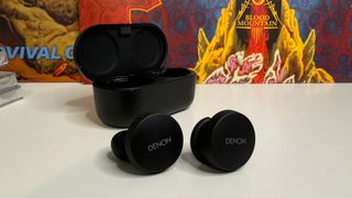 Denon PerL earbuds out of the case in front of a record