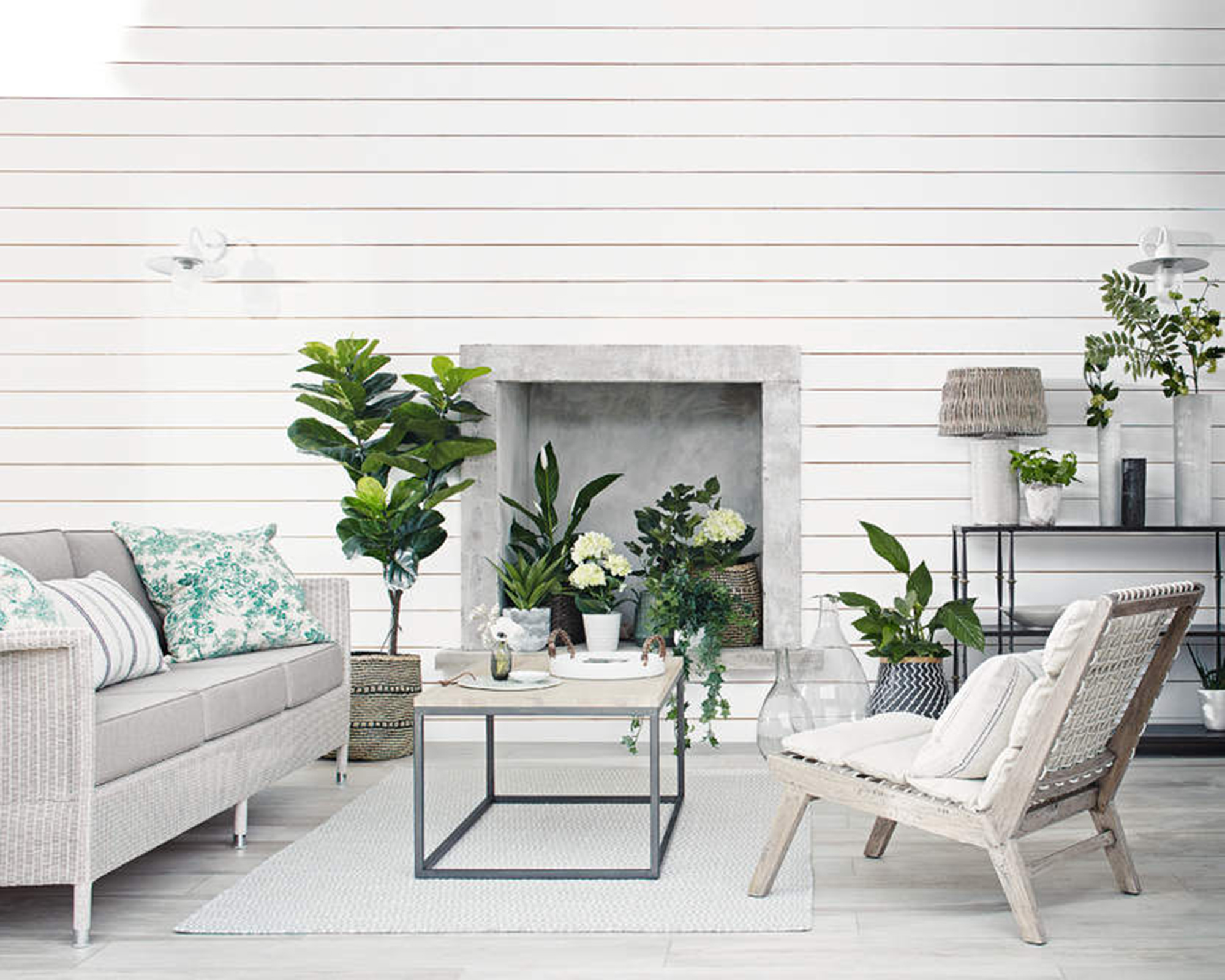 Airy living room with fireplace filled with real and faux potted plants.