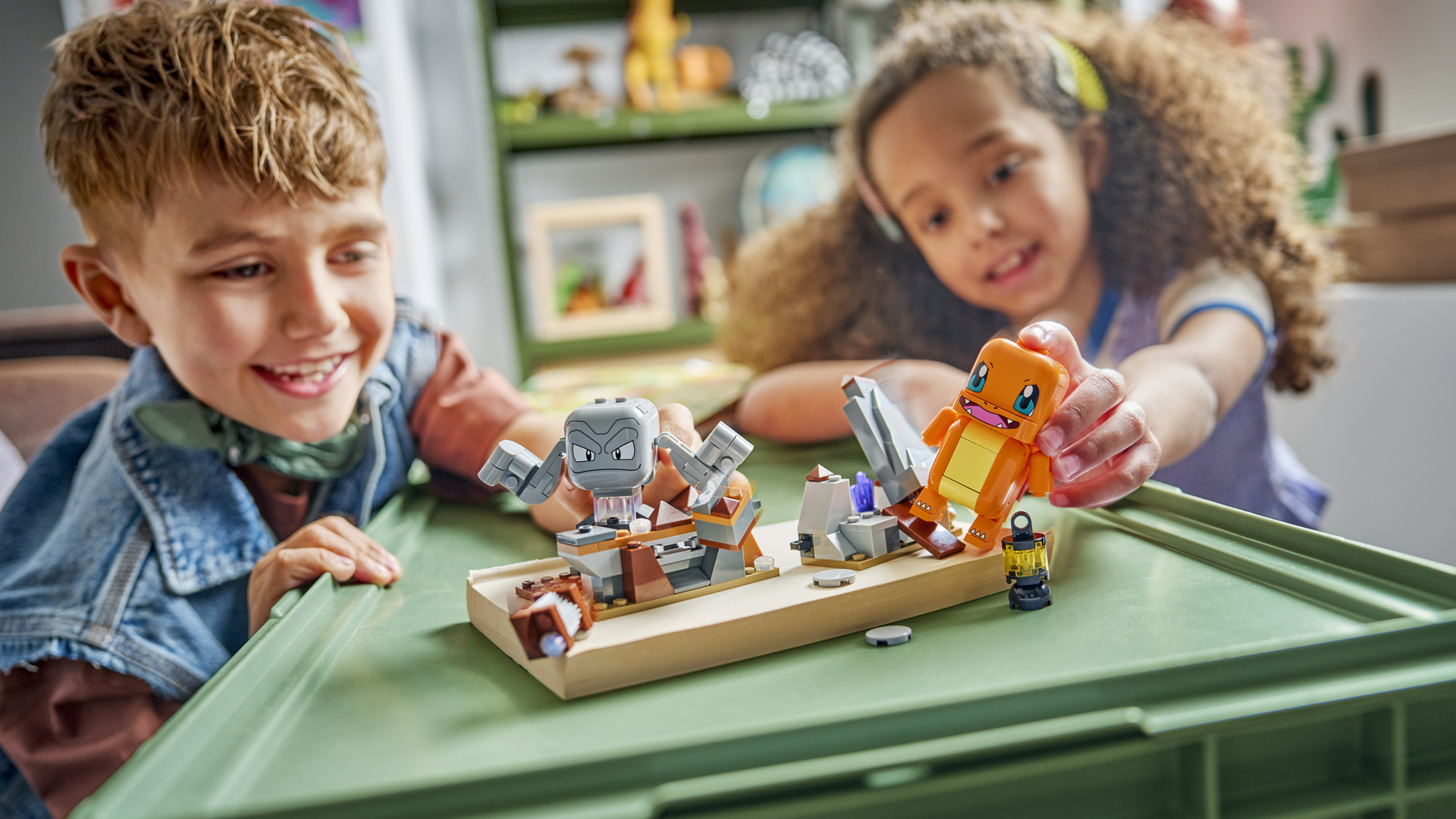 Two children smile while playing with the Charizard vs. Geodude Pokemon Lego set
