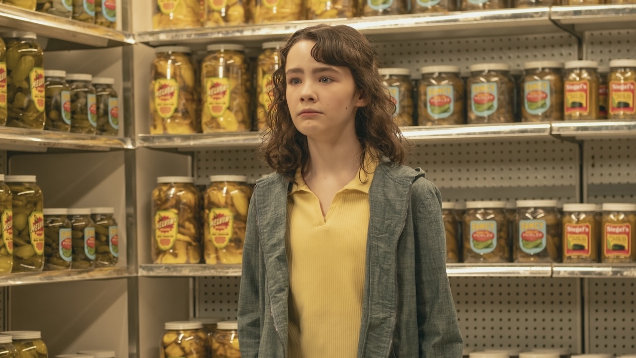 Lilly standing in front of so many pickle jars in IT: Welcome to Derry Episode 2