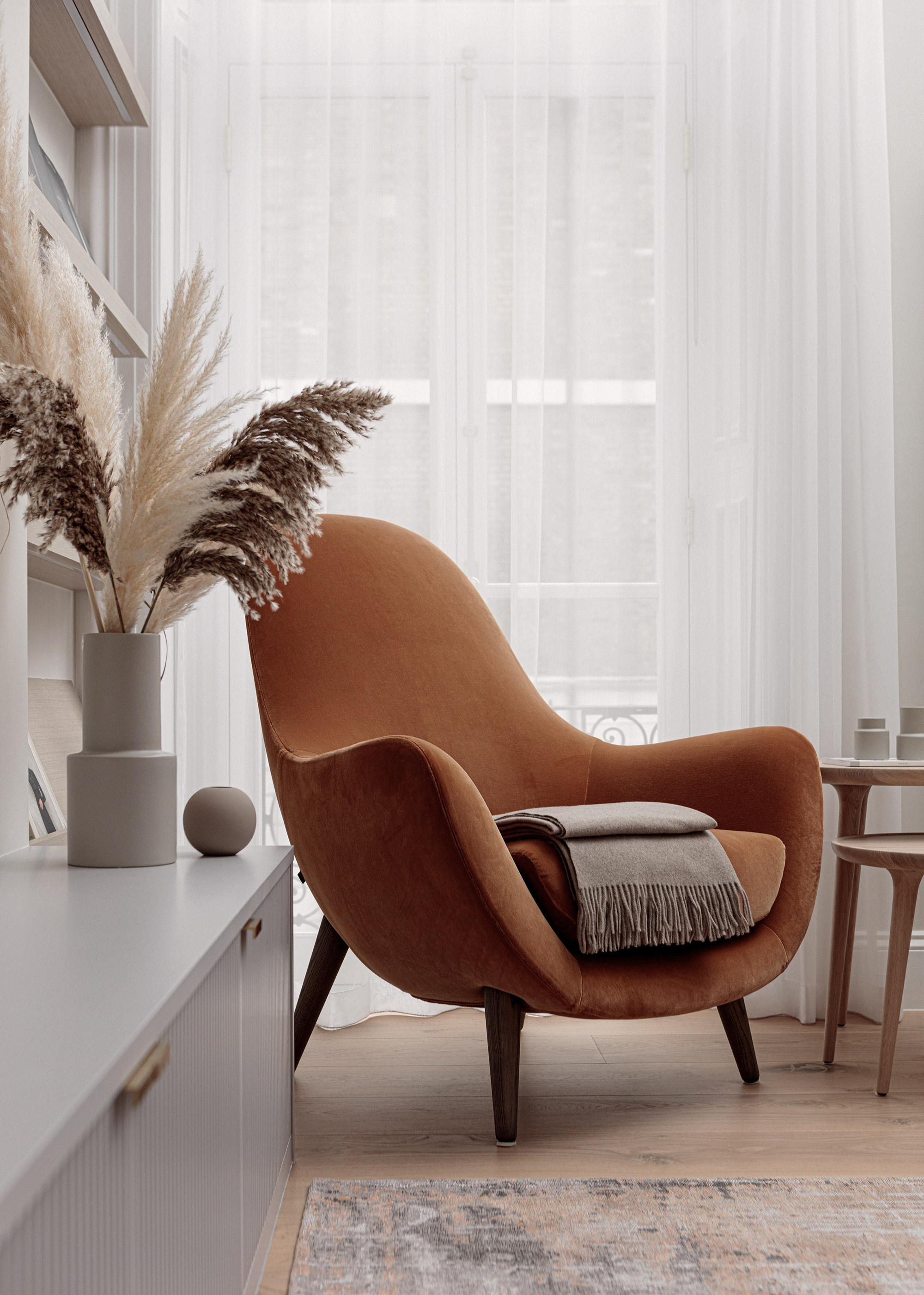 A cozy living room corner with an orange sofa chair with a folded fringe throw