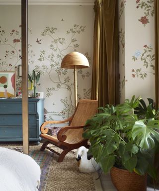 floral mural wallpapered bedroom with vintage blue chest of drawers and a small rattan and wooden chair