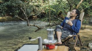Man relaxing with a hot drink at camp