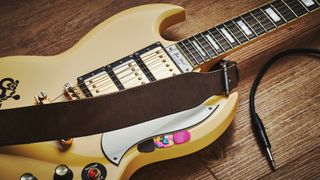 Cream Gibson Les Paul SG with a brown leather guitar strap