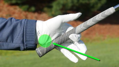 A golfer holding a golf club between his index finger and the palm of his hand