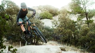 Pivots new Shadowcat bike being jumped over a rock feature by a woman rider