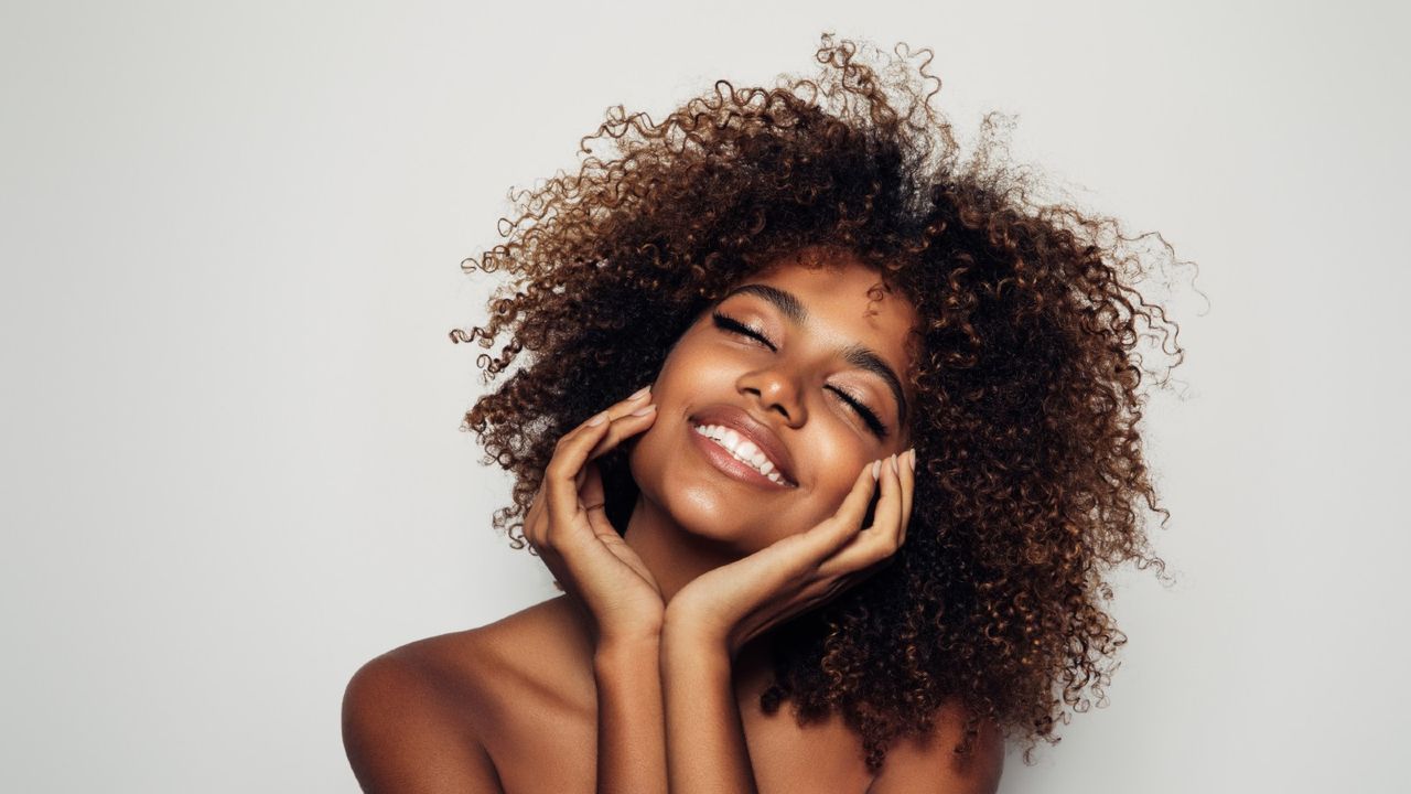 woman smiling with hands on chin