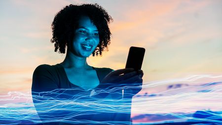 A woman smiles as she uses AI on her phone.