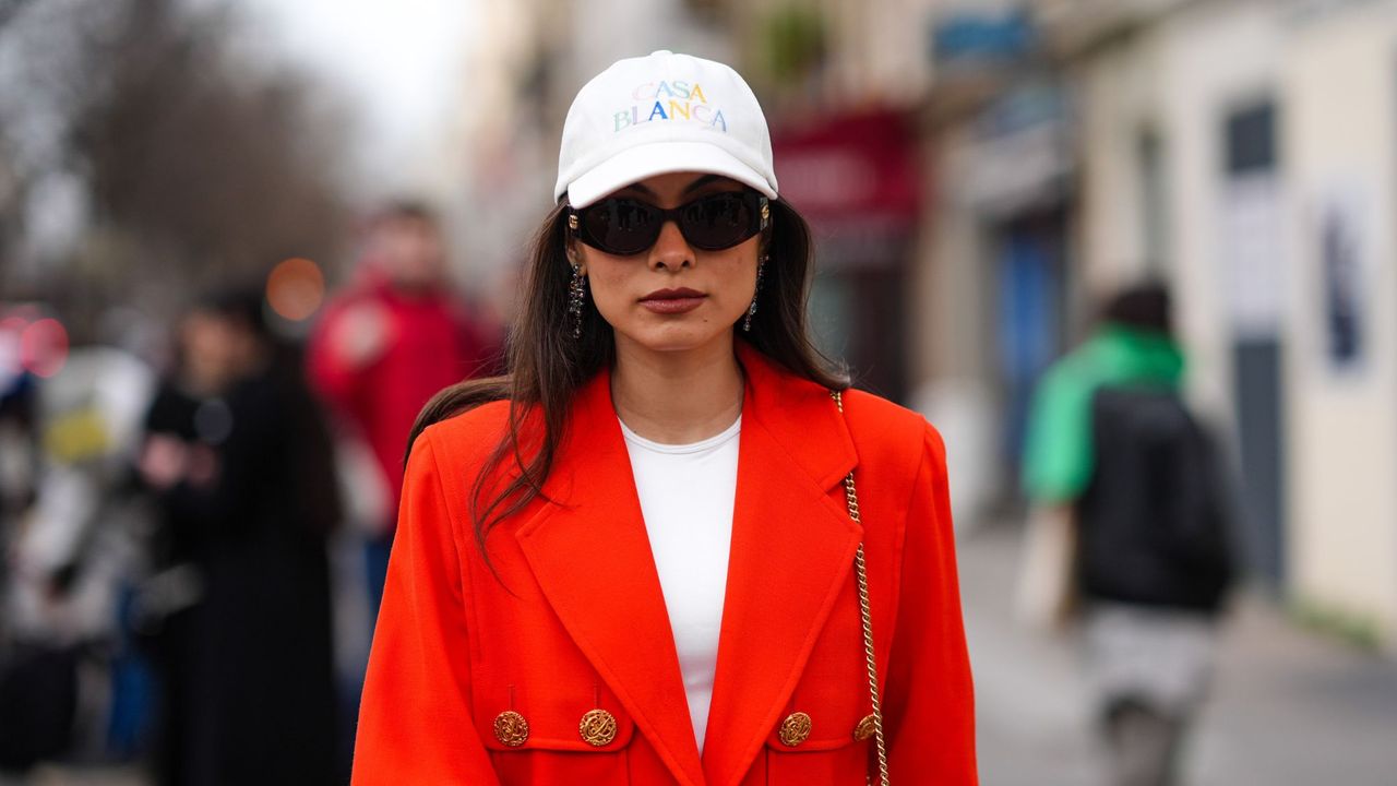 woman with white cap and red blazer with sunglasses on