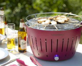 a tabletop outdoor grill with skewers of meat cooking