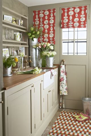 A country style faucet area with fresh flowers and shelving displaying decorative items