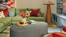 Colorful seating room area featuring a painterly rug, swirl-upholstered irregularly shaped ottoman, and a woven floor lamp 