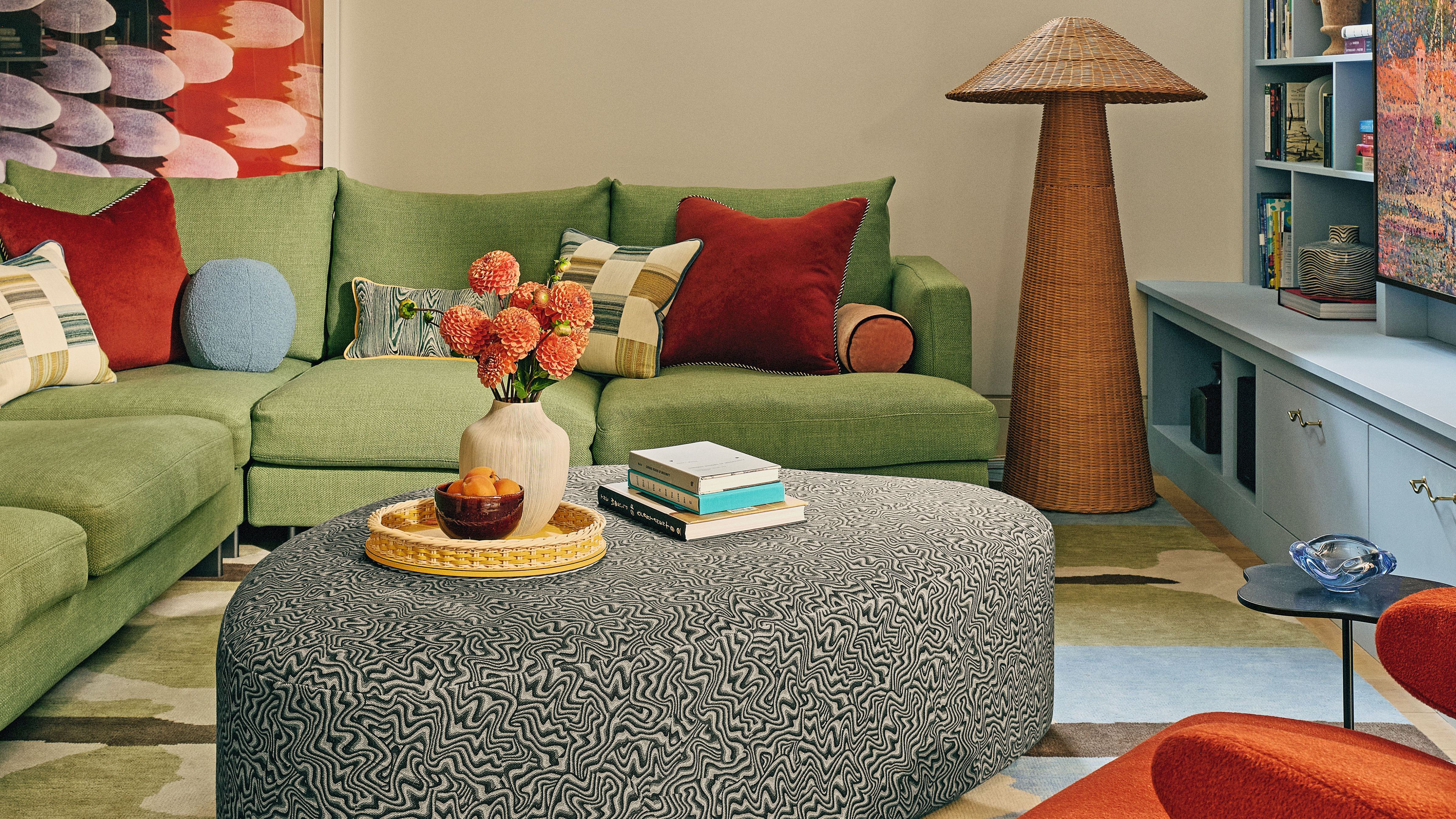 Colorful seating room area featuring a painterly rug, swirl-upholstered irregularly shaped ottoman, and a woven floor lamp 