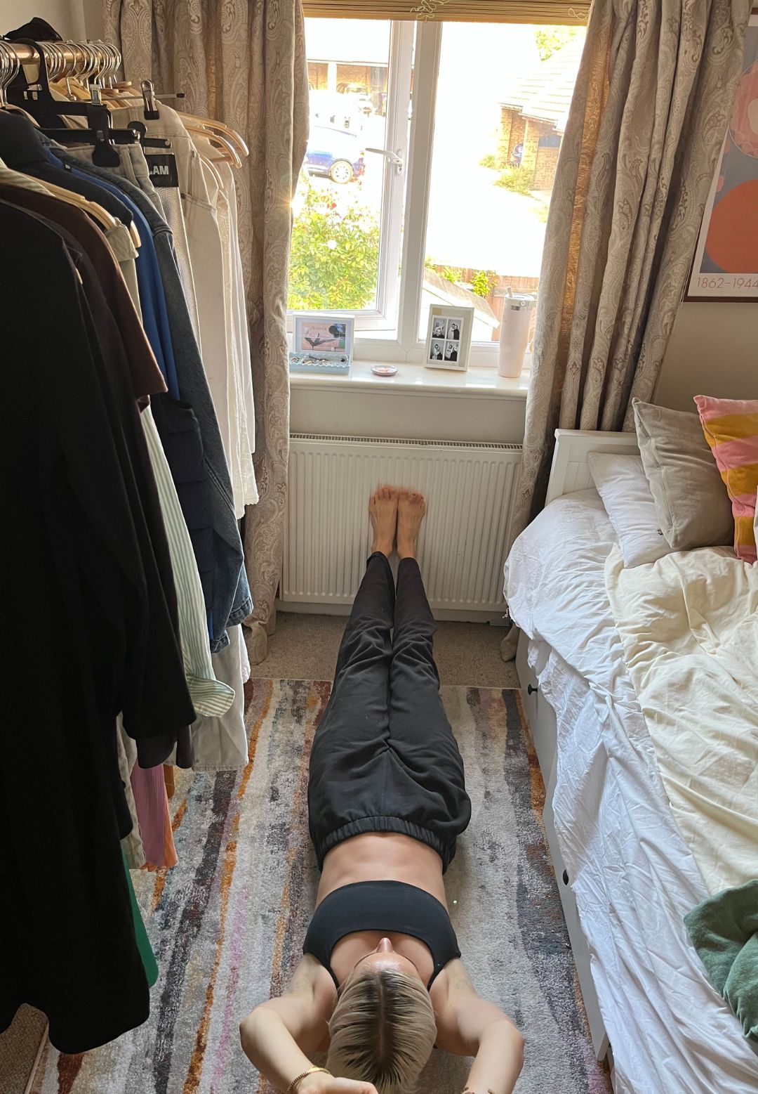 A woman practicing a hollow hold exercise on her bedroom floor