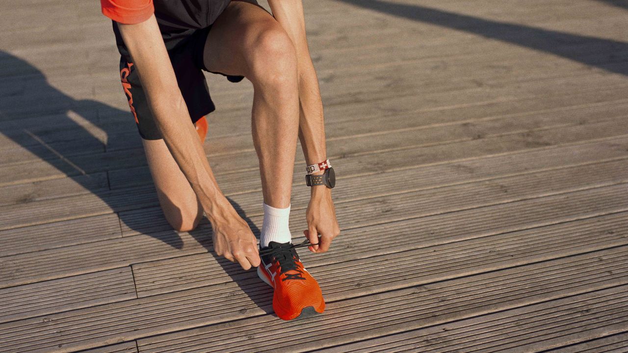 Person tying their shoelaces on a wooden decking