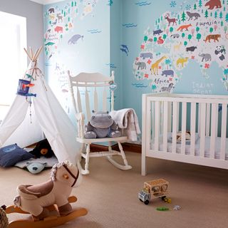Blue nursery with white cot, world map wall mural and a white teepee play area