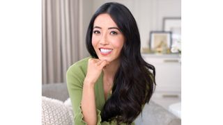 Image of Susie Ma smiling with long black curled hair and wearing a green fine-knit dress