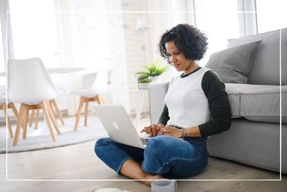 woman sitting on the floor with laptop in front of sofa