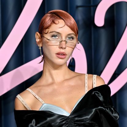 a white woman with short red hair posing on a red carpet