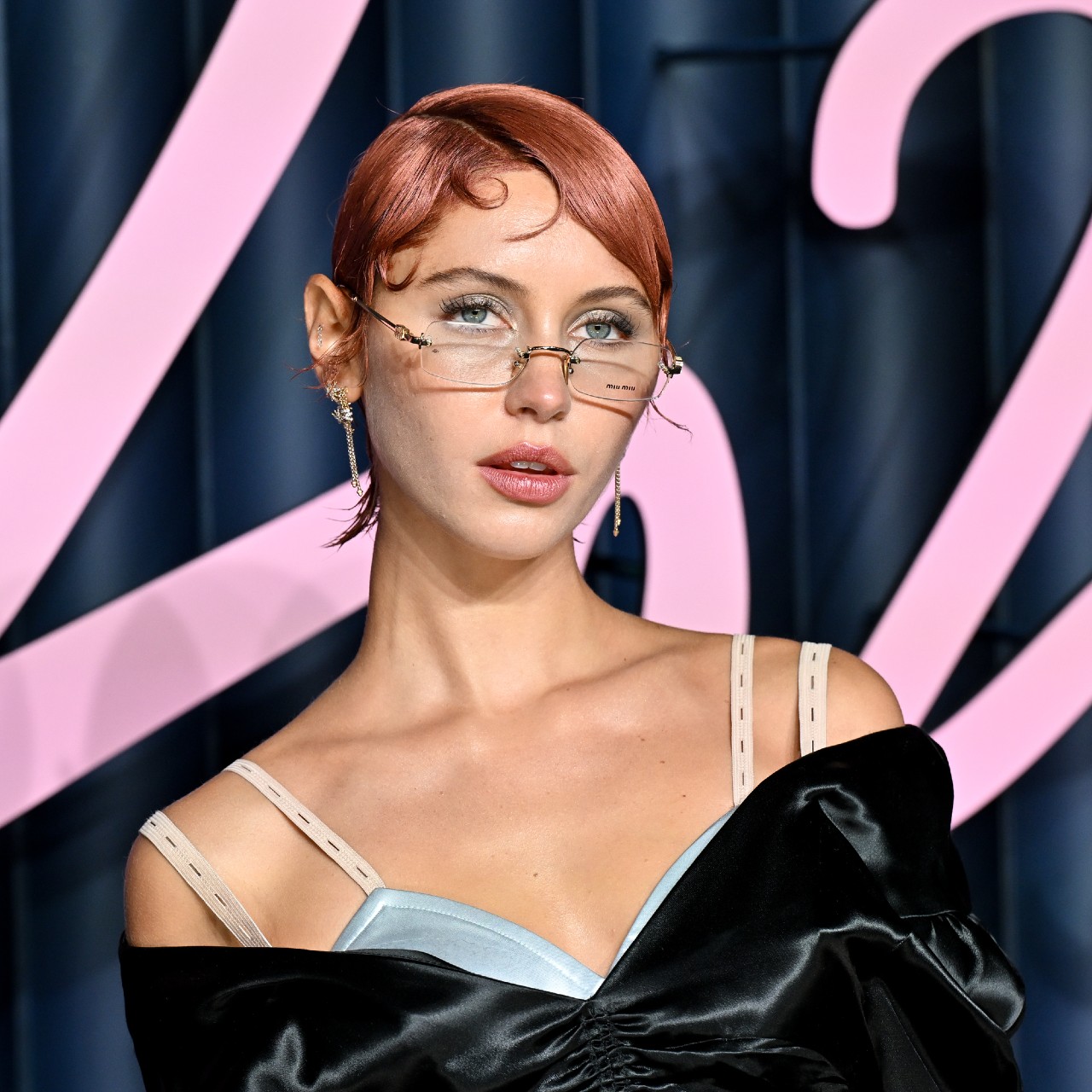 a white woman with short red hair posing on a red carpet