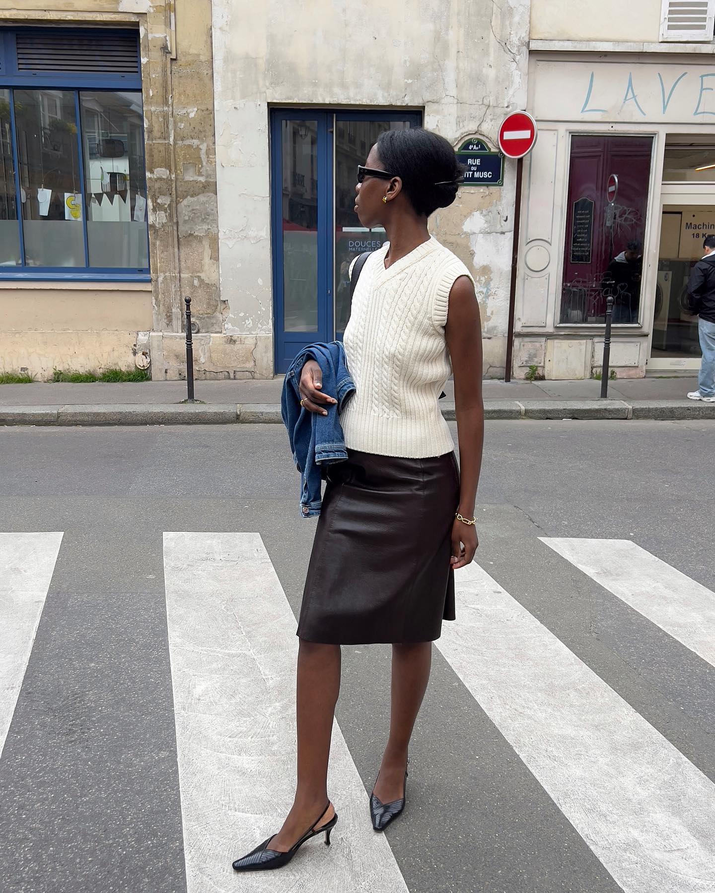 An image of @sylviemus_ wearing a white argyle sweater vest with a leather midi skirt and a slingback heel.