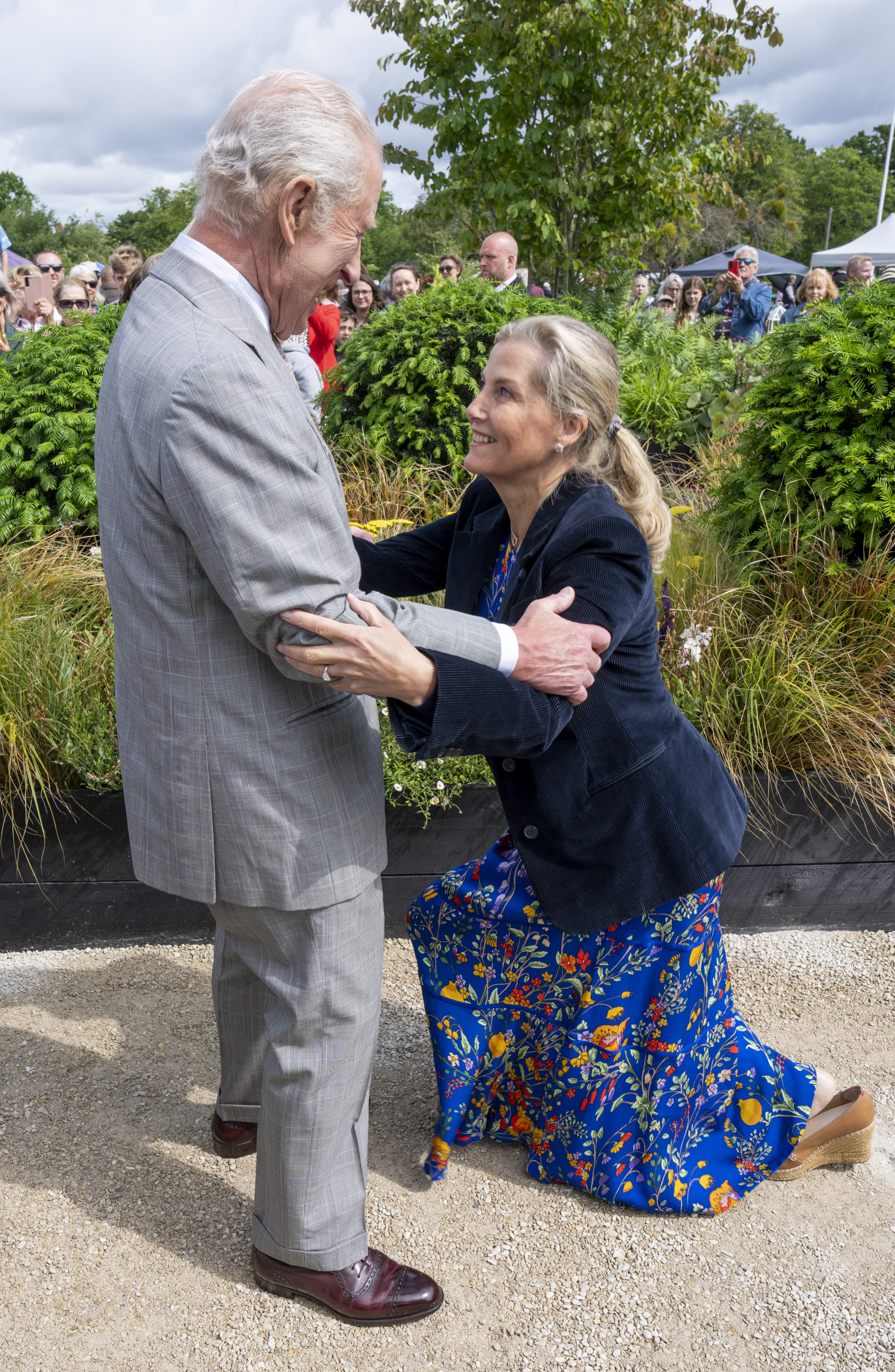 Duchess Sophie curtseying to King Charles in a blue floral dress at a flower show