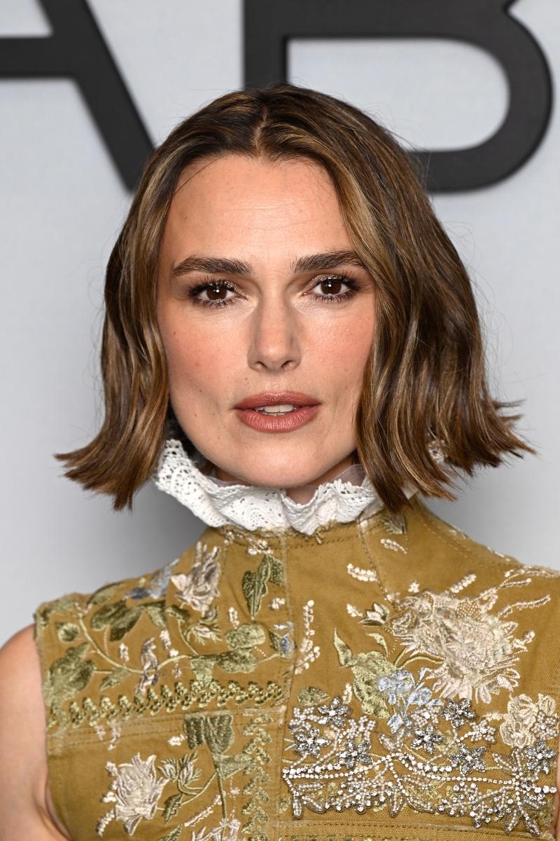 Keira Knightley is pictured with a wavy bob and wearing a floral embellished high-neck dress with a collar at the "The Woman In Cabin 10" special screening at BAFTA on September 25, 2025 in London, England.