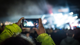 A festival goer takes a photograph on a mobile phone at Download Festival 2015.