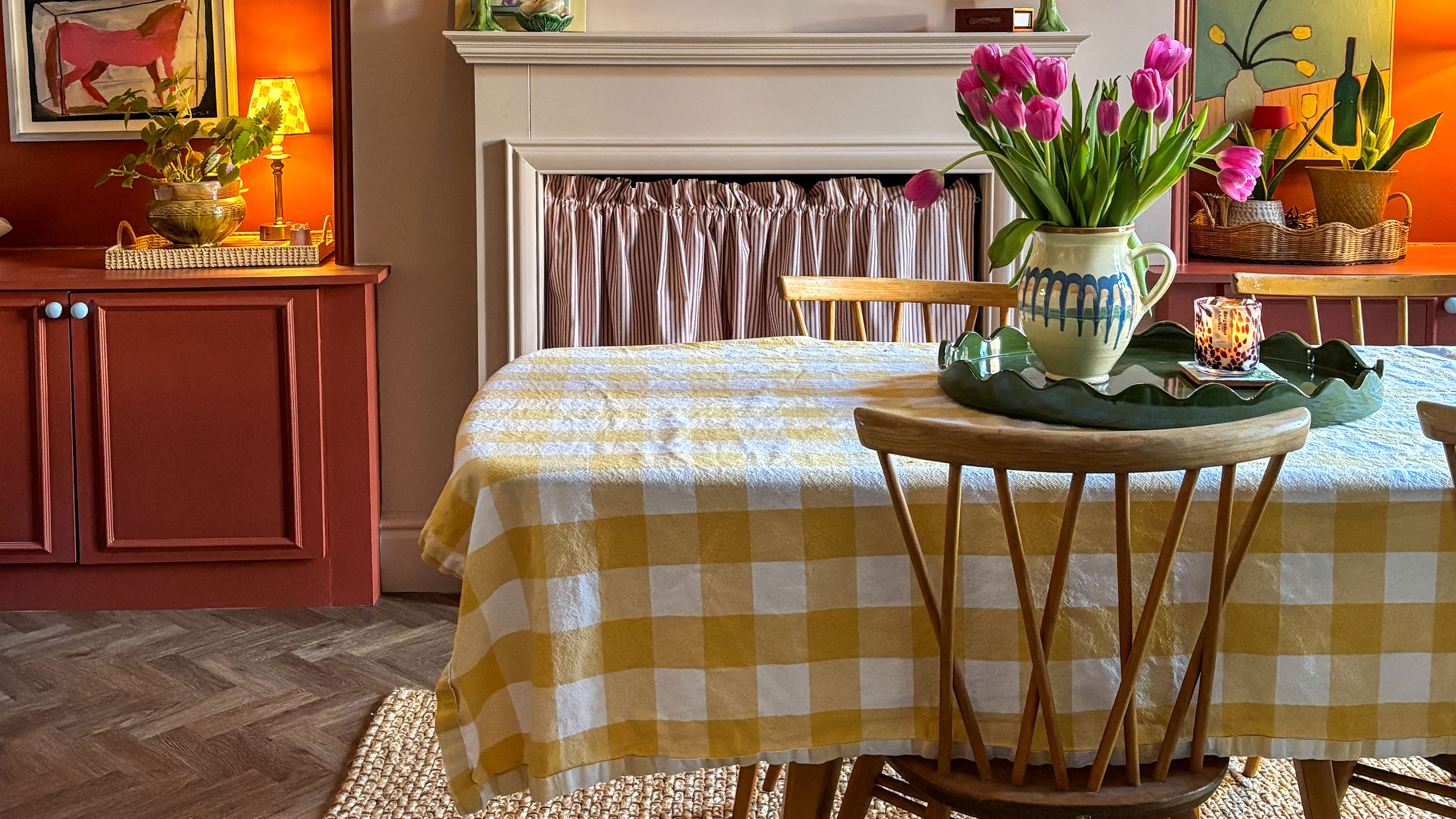 Dining room with neutral walls, terracotta built-in storage and table covered in yellow and white gingham tablecloth