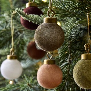 multicolored flocked Christmas ornaments hanging on a a Christmas tree