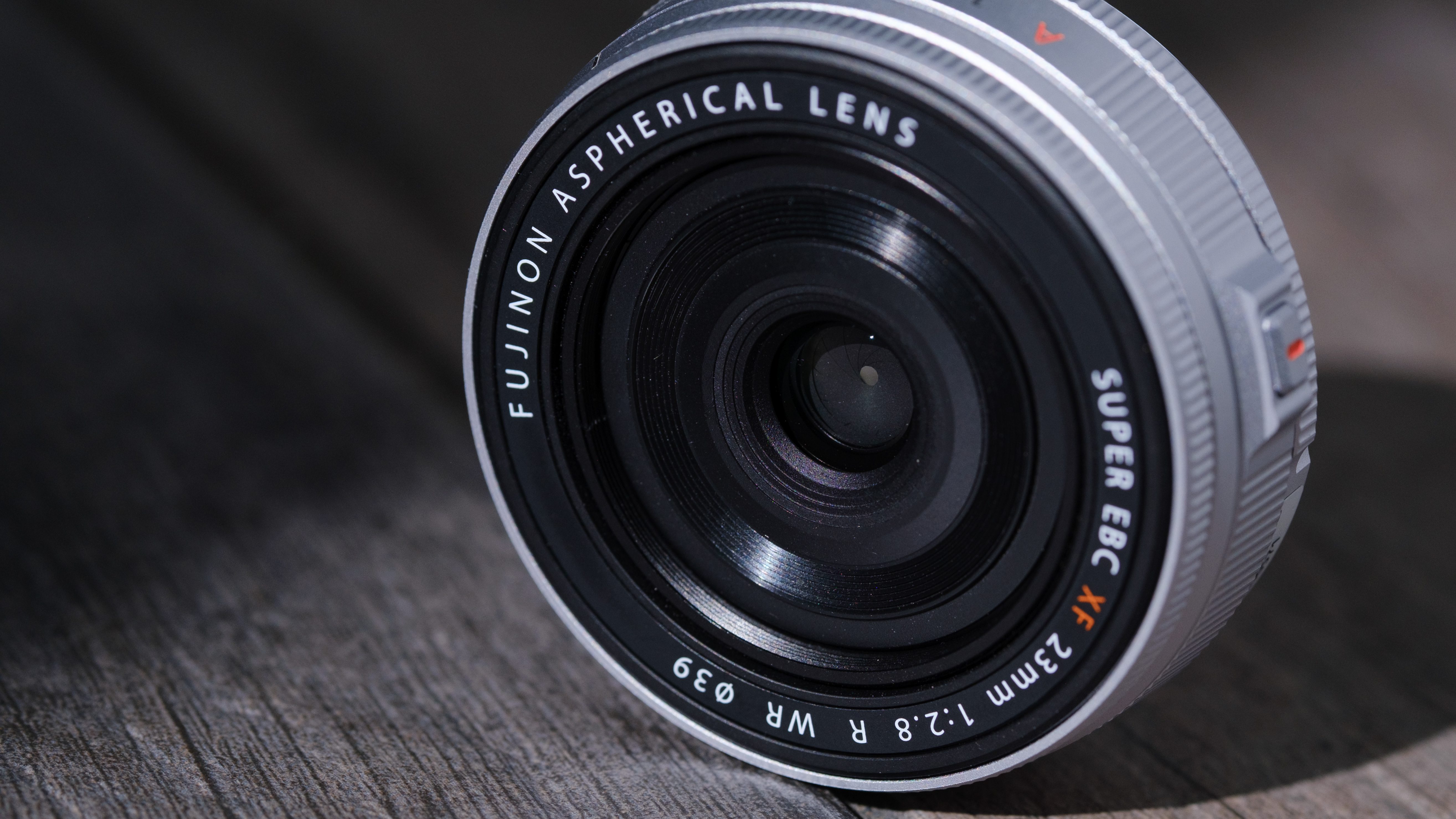 The Fujifilm XF 23mm f/2.8 R WR on a gray wood-like surface