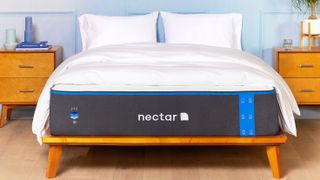 The Nectar Memory Foam Mattress sat on a wooden bed frame and dressed with a white comforter and white pillows