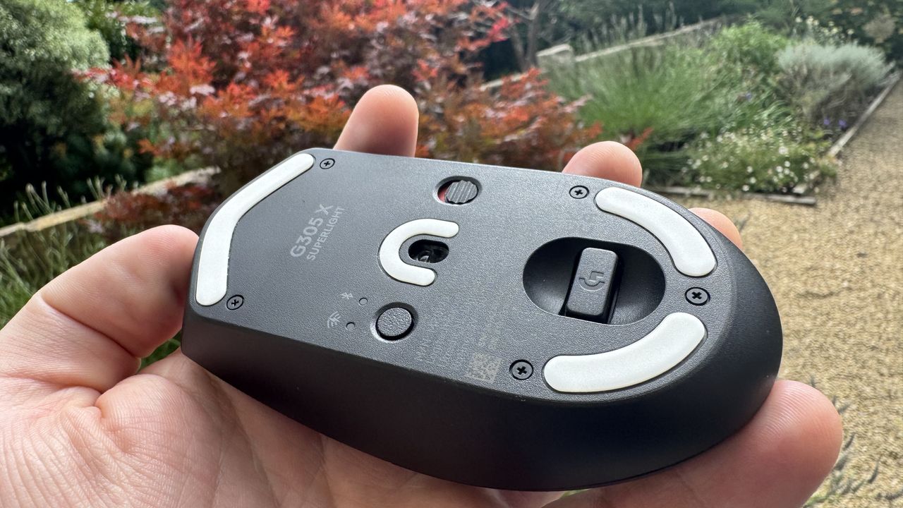 Logitech G305 X Superlight gaming mouse, held in a hand outside