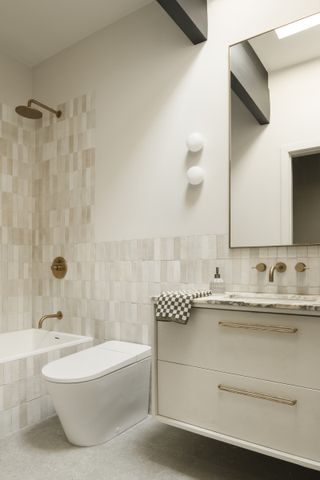 A bathroom with neutral zellige tiles, a built-in bath, and a marble top vanity